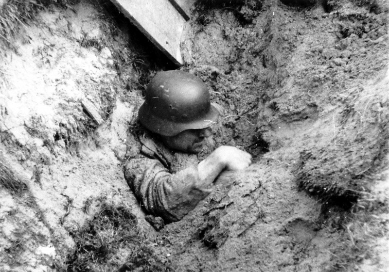 Засыпанный землей при близком взрыве авиабомбы немецкий солдат пытается выбраться. Он действительно жив — есть кинохроника с этим эпизодом, где видно, как солдат рукой разгребает землю. вов, фото