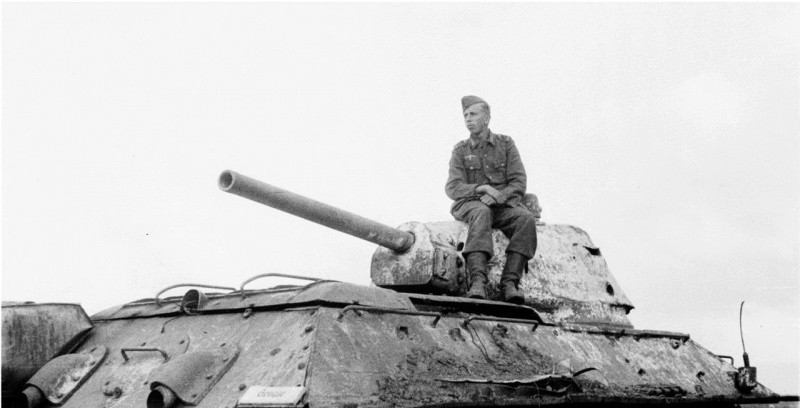 Немецкий солдат позирует, сидя на башне подбитого в поле советского танка Т-34. По характерным признакам машина выпуска апреля 1943 года и производства завода №112 «Красное Сормово». вов, фото