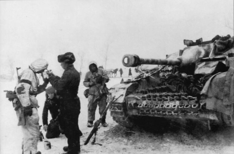 Немецкий солдат, вооруженный штурмовой винтовкой StG 44 прикуривает у самоходчика из экипажа штурмового орудия StuG IV. вов, фото
