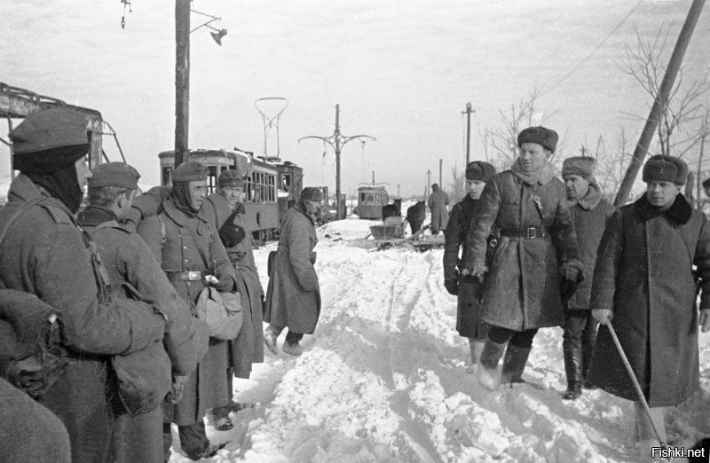 Советские офицеры проходят мимо немецких пленных, стоящих у разбитых трамвайных вагонов в Сталинграде.